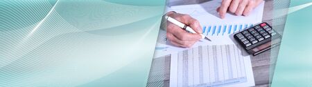Hand of an accountant working on financial documents with calculator; panoramic banner
