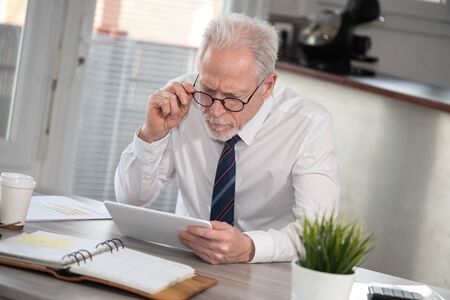 Senior businessman using digital tablet at workplaceの写真素材