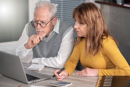 Two mature coworkers working on laptop at officeの写真素材