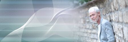 Portrait of handsome mature man standing against a wall, outdoors; panoramic bannerの写真素材