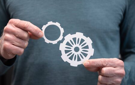Man holding two paper cogwheels; Concept of business cooperation