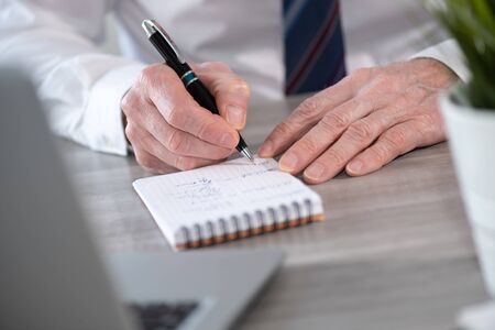 Male hands with pen writing on notepad