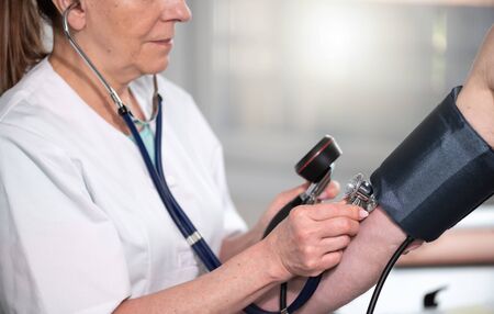 Female doctor measuring blood pressure with sphygmomanometerの写真素材