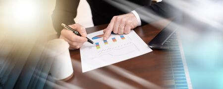 Businessman analysing marketing graphs at office; multiple exposure
