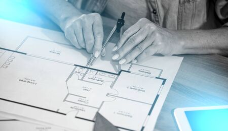 Female architect working on blueprint of new construction project; light effect