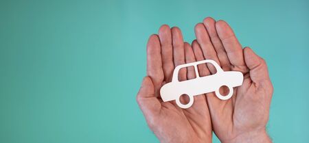 Concept of auto insurance with paper car in hands on turquoise color backgroundの写真素材