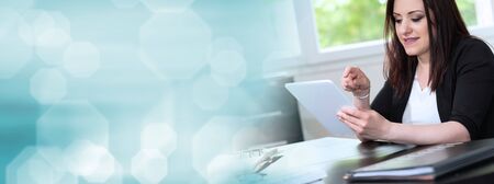 Businesswoman using digital tablet at workplace; panoramic bannerの写真素材