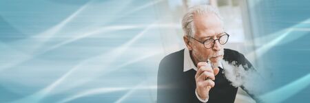 Portrait of senior man smoking electronic cigarette; panoramic bannerの写真素材