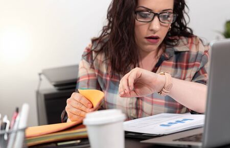 Stressed young businesswoman looking at her watch