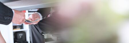 Businessman giving money under a table; panoramic bannerの写真素材
