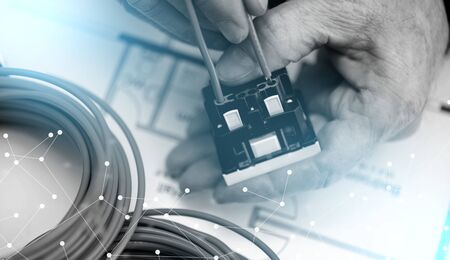 Electrician hands connecting a wire into a power socket; light effect