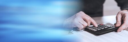 Male hand using calculator, accounting concept; panoramic banner
