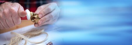 Plumber preparing fitting sealing with hemp fibers; panoramic banner