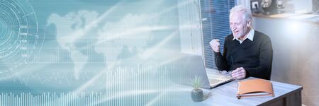 Smiling senior businessman showing success gesture in front of his laptop; panoramic banner