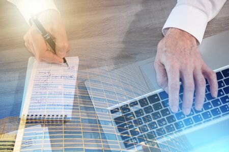 Hand of businessman taking notes while using laptop; multiple exposure