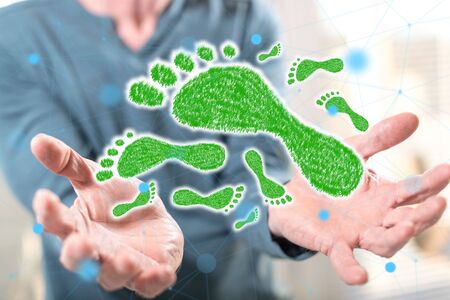 Carbon footprint concept above the hands of a man in backgroundの写真素材