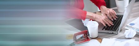 Businesswoman working on a cluttered and messy desk; panoramic banner