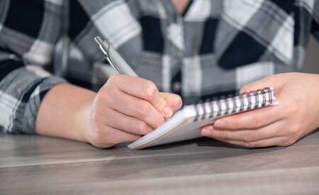Female hands taking notes on notepad