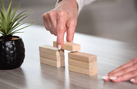 Female hand building a bridge with wooden blocks; concept of association
