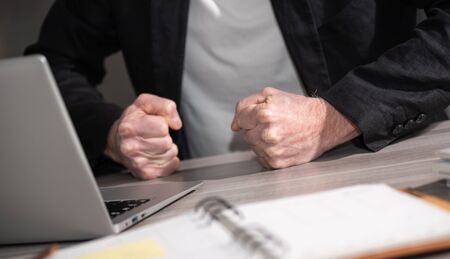 Angry businessman hitting his desk with his clenched fistsの写真素材