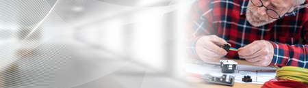 Senior electrician connecting wires in terminal block; panoramic bannerの写真素材