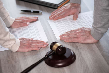 Hands of couple in conflict position during divorce. Concept of divorce with judge gavelの写真素材