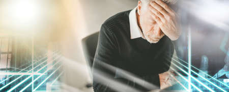 Stressed businessman sitting in office with hand on forehead; multiple exposureの写真素材