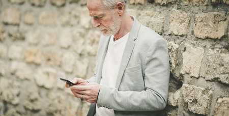 Mature man using his mobile phone outdoorsの写真素材