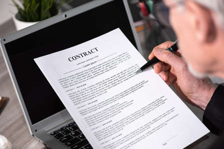 Senior man checking content of a contractの写真素材