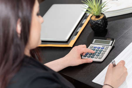 Businesswoman using calculator and working on financial dataの写真素材