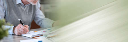 Businessman working on financial results and taking notes on notepad; panoramic banner
