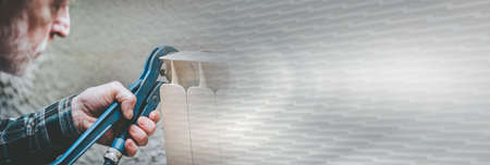 Repairman working on radiator with wrench; panoramic banner