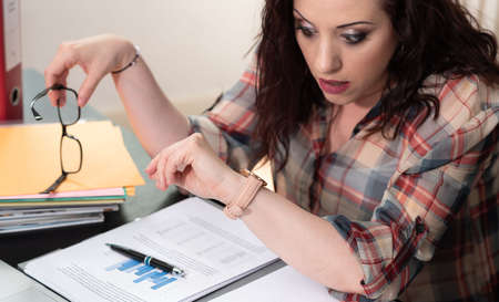 Stressed young businesswoman looking at her watch