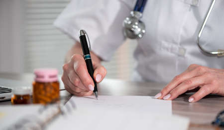 Female doctor writing prescription in medical officeの写真素材