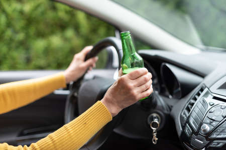 Woman drinking alcohol while drivingの写真素材