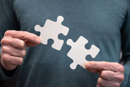 Hands joining two puzzle pieces, teamwork conceptの写真素材