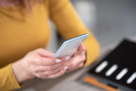 Woman holding and using her mobile phone