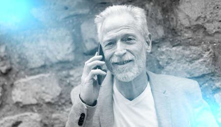 Mature man using his mobile phone outdoors; light effectの写真素材