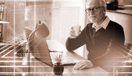 Senior businessman having a coffee break at office; light effectの写真素材