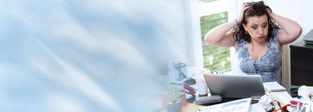 Overworked young businesswoman sitting at a messy desk; panoramic banner