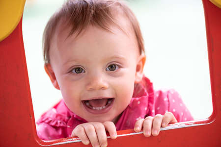 Cute baby girl having fun on a playground and looking at the cameraの写真素材
