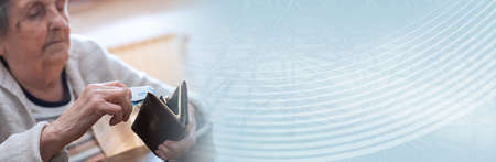Elderly woman taking out a banknote from her wallet; panoramic bannerの写真素材