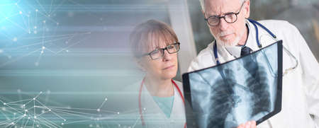 Two doctors examining x-ray report in medical office; panoramic banner