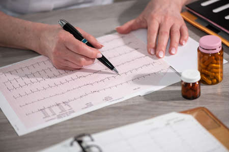 Female cardiologist examining an ecg graph in medical office