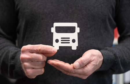 Man holding a paper bus; Concept of bus insuranceの写真素材