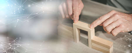 Male hand building a bridge with wooden blocks; concept of association; panoramic banner
