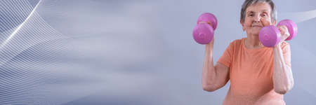 Happy senior woman holding dumbells; panoramic bannerの写真素材