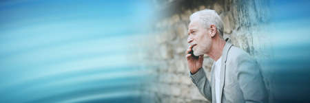 Mature man using his mobile phone outdoors; panoramic banner