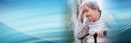 Elderly woman sitting and having headache; panoramic bannerの写真素材