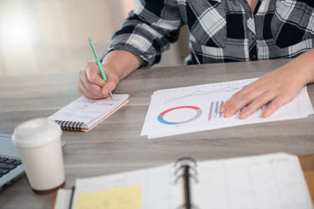 Businesswoman analyzing marketing data and taking notes